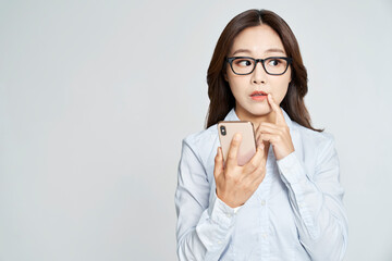 Young business woman posing with smartphone in studio shot - obrazy, fototapety, plakaty