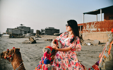 casual pretty girl side pose sitting camel at beach indian pakistani model
