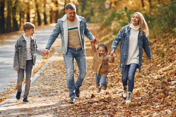 Near the road. Happy family is in the park at autumn time together