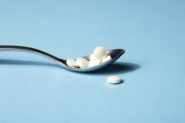 Dietary supplements. Vitamin tablets in an iron spoon on a blue background. Complementary and medical products
