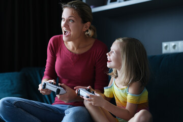 Little girl with her mother play video games, close-up