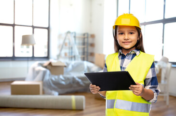 repair, moving and profession concept - smiling little girl in protective helmet and safety vest with tablet pc computer over living room with stuff background