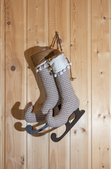 Toy boots made of fabric with skates on a wooden wall. The concept of Christmas and gifts