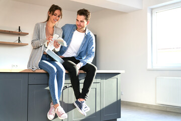 Caucasian couple in new kitchen holding paint palette to discuss