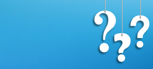 White question marks suspended by ropes with copy space on blue background