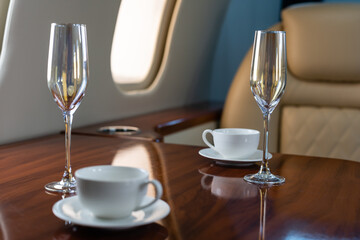 Interior of a business class of a commercial passenger plane, an armchair and a window, a table and a cocktail glass with a drink