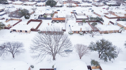 Top view heavy snow covered suburban houses roofs and cars at residential street near Dallas, Texas, USA