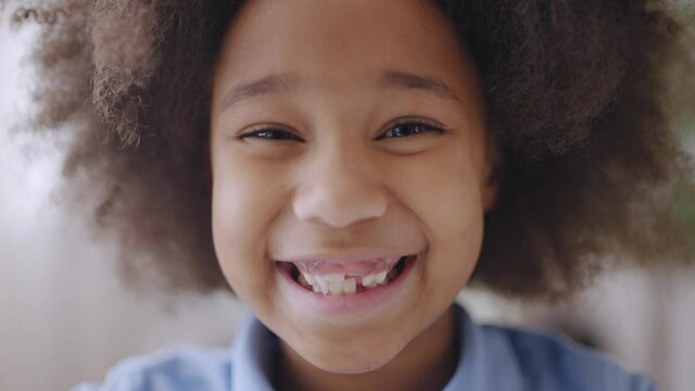 Adorable kid with afro hair smiling at camera, child's teeth, dental health