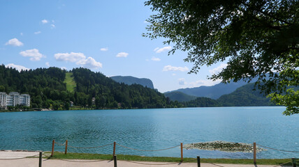 View of lake Bled in Slovenia, walking path and surrounding mountains during a sunny day