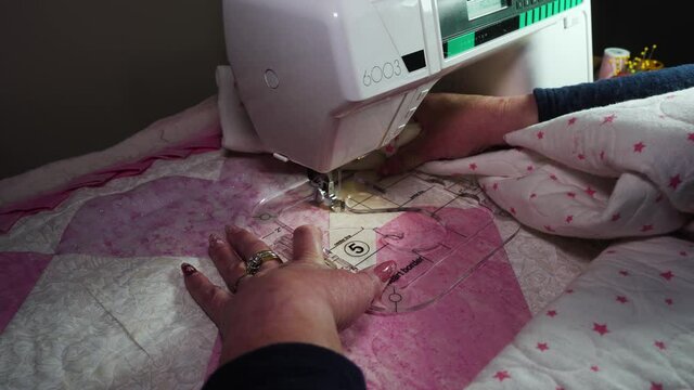 Using a plastic template fitted on a sewing machine to stitch a pattern into a handmade quilt - isolated