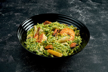 Wok rice with shrimps and mussels on a black stone background. 45 degree angle view. Close-up, selective focus