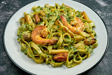 Noodles with shrimps and mussels on a black stone background. 45 degree angle view. Close-up, selective focus