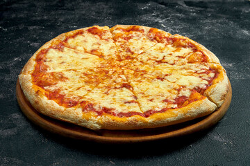 Pizza with melted cheese on a black stone background. 45 degree angle view. Close-up, selective focus