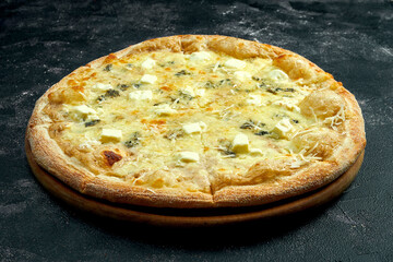 Pizza with 4 types of cheeses on a black stone background. 45 degree angle view. Close-up, selective focus