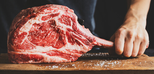 Butcher cuting fresh meat tomahawk steak