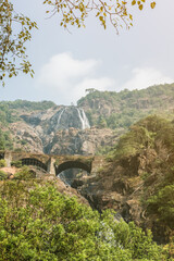 Fototapeta na wymiar Dudhsagar waterfall and old bridge in Indian state of Goa on a sunny day.