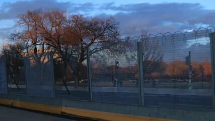 The U.S. Capitol behind security fencing and razor wire following the January 6th 2021 riots. The camera pans left to right. Unidentifiable National Guardsmen are seen behind the fencing. Washington, 