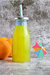 Vertical shot, glass bottle with refreshing orangeade, 
stone base in light colors and copy space.