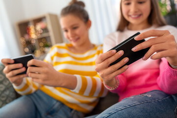 Fototapeta premium people, technology and friendship concept - close up of happy teenage girls with smartphone sitting on sofa at home