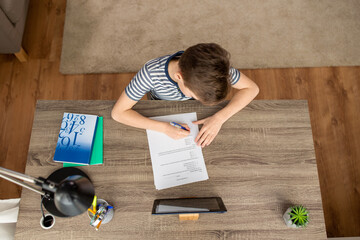 children, education and distant learning concept - student boy with tablet pc computer and books on table doing school test at home