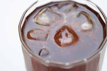 Close-up top view of brown drink with ice in a glass