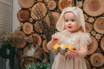 Child Girl wearing bunny ears and sitting with white ducklings on the wooden background. 