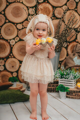 Child Girl wearing bunny ears and sitting with white ducklings on the wooden background. 