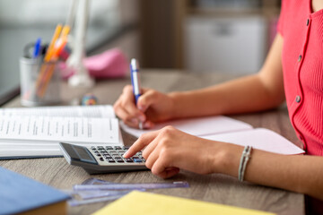 Fototapeta premium school, education and learning concept - close up of teenage student girl counting on calculator at home