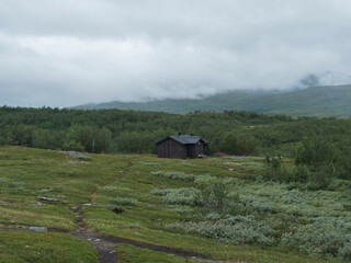 Sami village Staloluokta at Virihaure lake with houses and cottage, mountains and birch trees. summer moody and foggy day at Padjelantaleden hiking trail. Sweden Lapland landscape