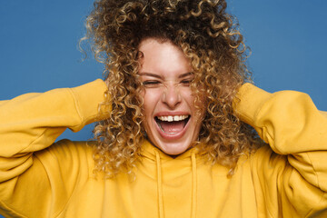 Blonde woman dressed in hoodie laughing and holding her head