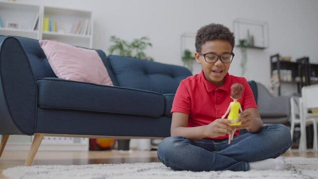 Happy African American boy playing with a doll, no to gender stereotypes in toys