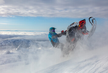 extreme driving of a mountain snowmobile. a sports snowmobiler in bright clothes and a helmet without brands, a colorful snowmobile of a new model. jumping with plumes and whirlwinds of snow