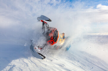 a beautiful and steep turn of a snowmobile in a close-up fall. a very rare photo of a snowmobile extreme with heavy snow in the frame. the concept of winter outdoor activities in the mountains