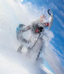 extreme driving of a mountain snowmobile. a sports snowmobiler in bright clothes and a helmet without brands, a colorful snowmobile of a new model. jumping with plumes and whirlwinds of snow