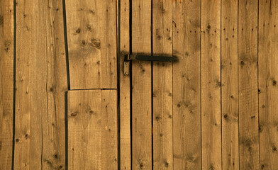 Barn door. Details of a door made of wood with black metal details at a cottage house from the farm.