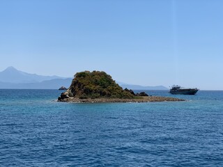 An uninhabited island in the Mediterranean. Islands surrounded by the sea, a quiet harbor for yachts. Seashore against the backdrop of mountains and clear sea.