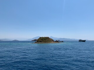 Fototapeta premium An uninhabited island in the Mediterranean. Islands surrounded by the sea, a quiet harbor for yachts. Seashore against the backdrop of mountains and clear sea.