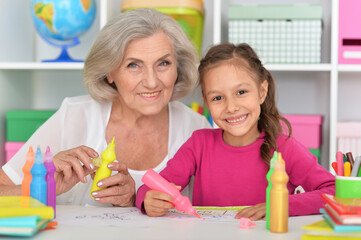 Porait of cute little girl drawing with her grandmother