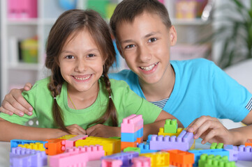 Brother and sister playing with colorful plastic blocks together