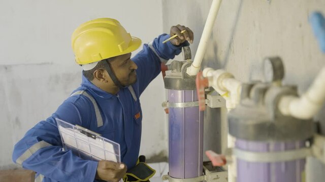 young indian plumber or repairman noting water level at under construction building - concept of professional occupation, and maintenance service.