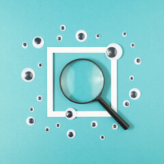 Magnifier and sticker eyes with a frame on a turquoise background. Search for truth minimal concept.