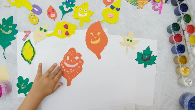 Autumn crafts. Child making colorful fun leaves from paper and plasticine. Back to school. Ideas for children's art and painting