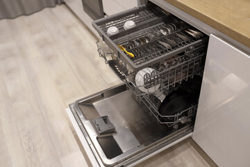 Open dishwasher with clean dishes at home white kitchen . High quality photo