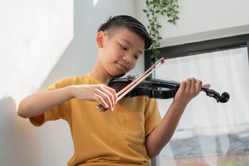 A Little Asian kid playing and practice violin musical string instrument against in home, Concept...