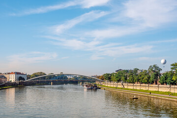 Fototapeta na wymiar Vistula River in Krakow and Father Bernatek Footbridge, pedestrian promenade on the right bank of the river. View in a sunny October day.