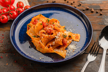 Pasta with tomatoes and parmesan, on a wooden background