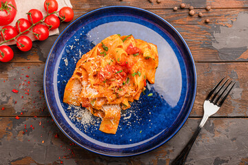 Pasta with tomatoes and parmesan, on a wooden background top view