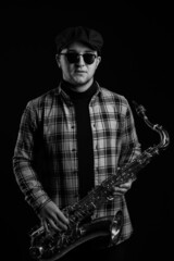Brutal Sexy Sax Player is Holding a Saxophone. Jazz Saxophonist has Tenor Sax. Black and White. Black Background. Close-up. High quality photo