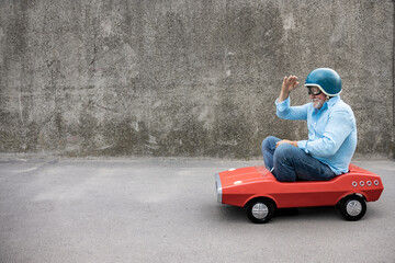 Funny businessman driving retro pedal car outdoor