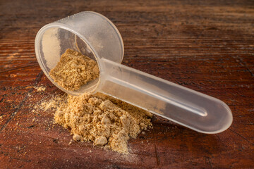 measuring scoop (teaspoon size) of maca root  powder against rustic weathered wood, superfood...